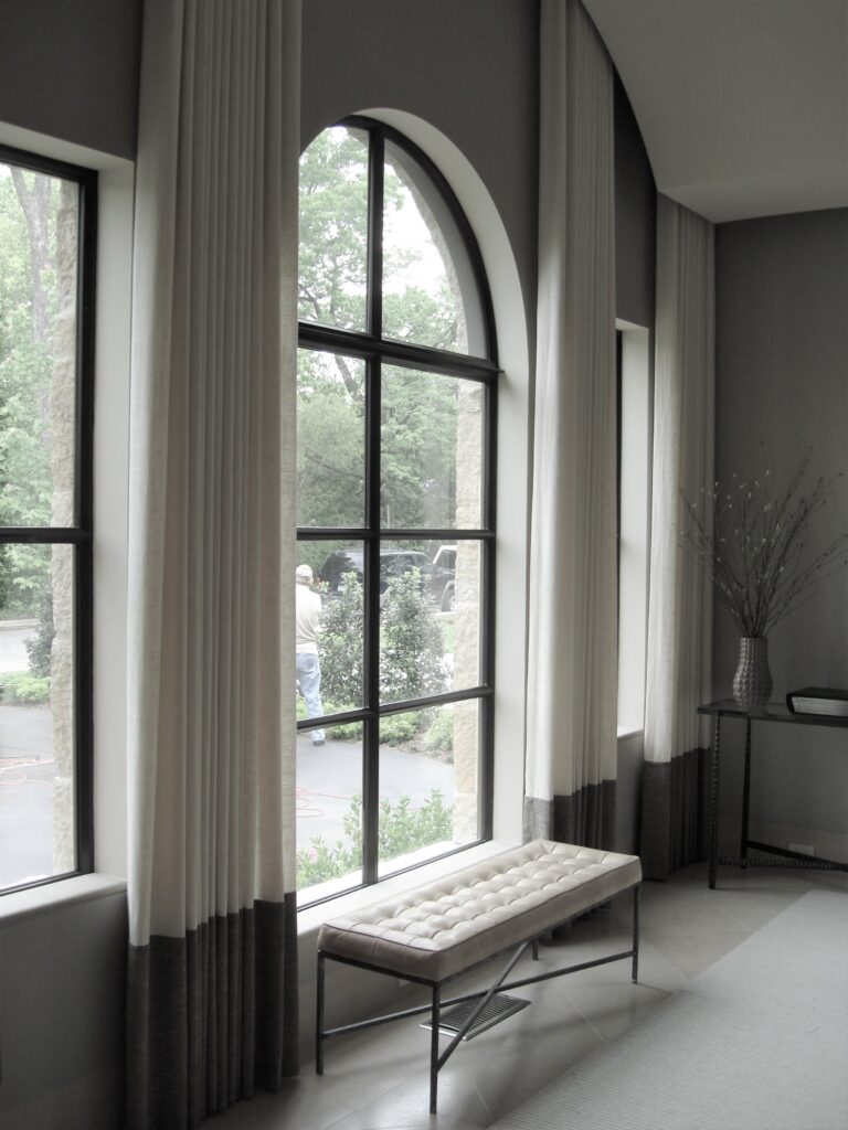 Large living room window with white and gray drapes