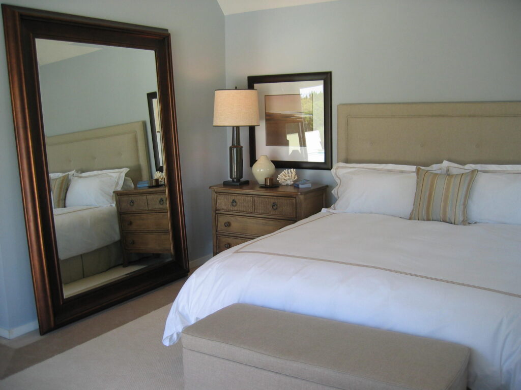 Tan and white bedroom with dark wood mirror